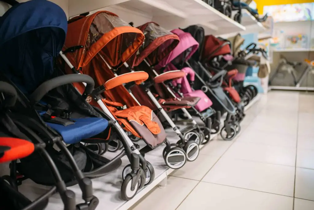 An image showing a row of 3 wheel and 4 wheel strollers in a store
